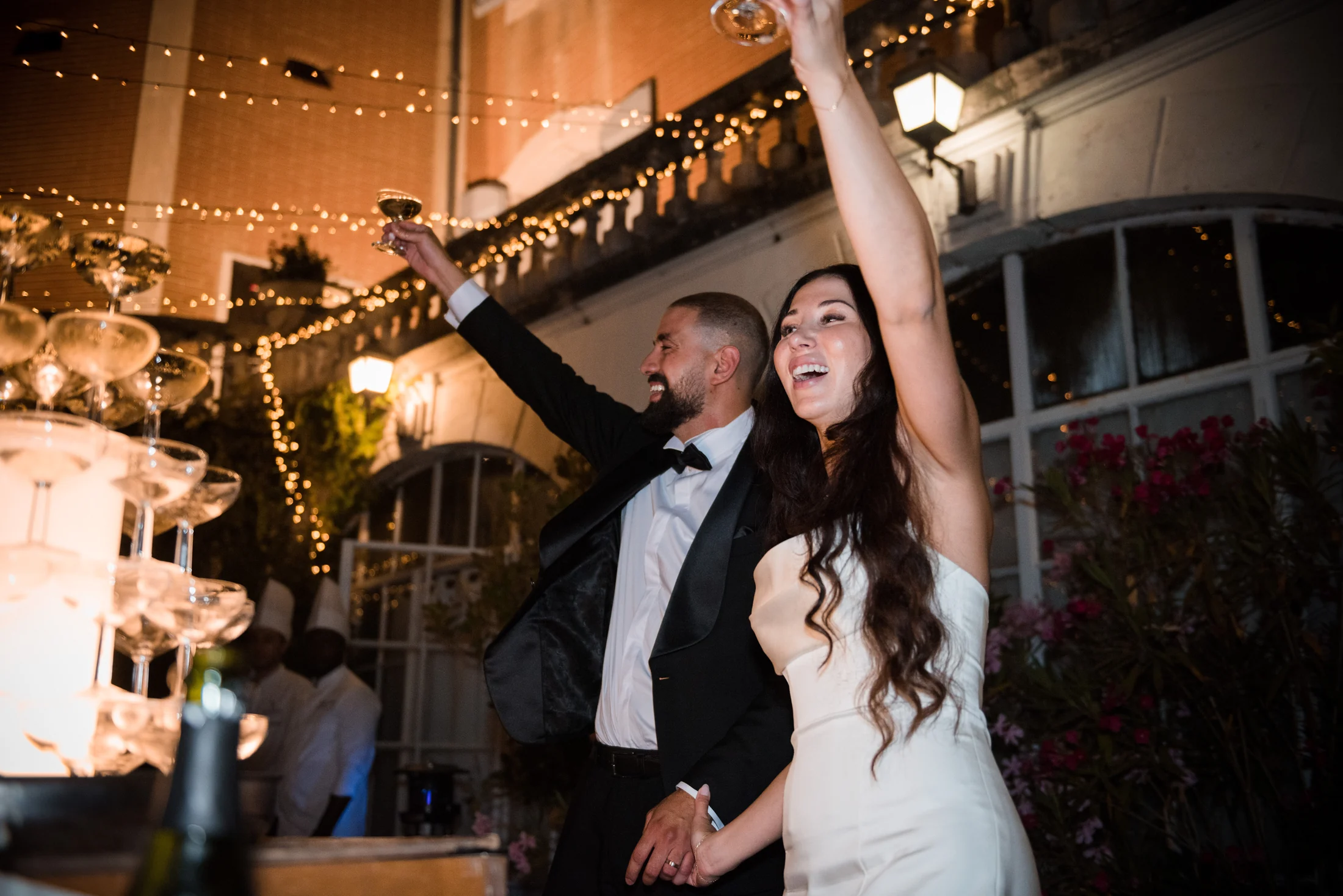 The newlyweds raising their glasses by the champagne tower